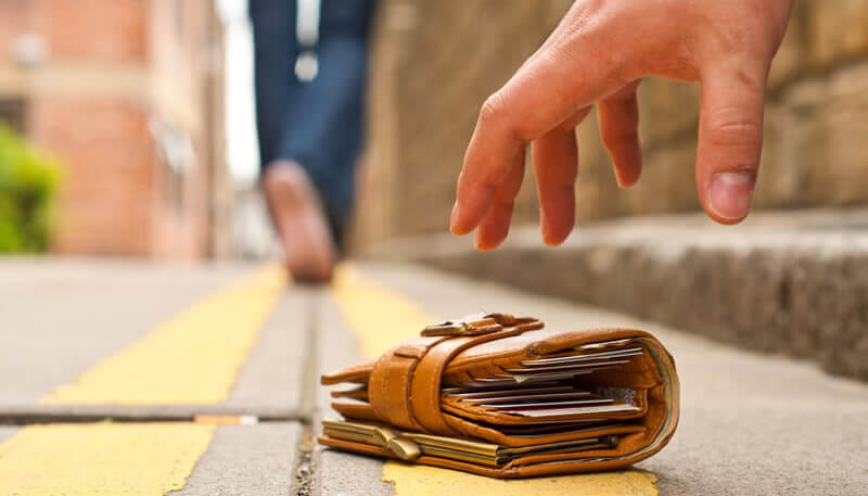 A thief reaching for a dropped wallet.
